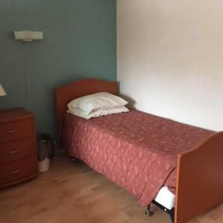 A simple bedroom with a single bed and a wooden dresser.