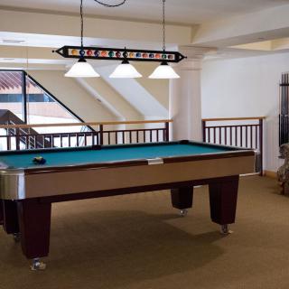 A well-lit game room featuring a billiards table.