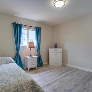 A minimalist bedroom with a bed, dresser, and nightstand by the window with blue curtains.