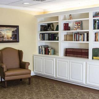 A cozy reading nook with a large bookshelf and an armchair.