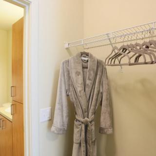 A bathrobe hanging in a closet with several empty hangers beside it.