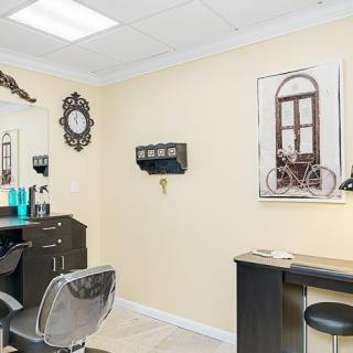 A well-decorated salon interior featuring styling chairs, a mirror, and elegant wall art.