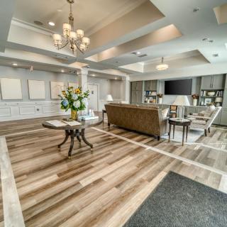 A spacious and elegantly designed living room with modern furnishings, a chandelier, and hardwood flooring.