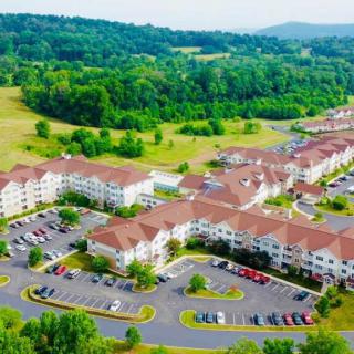 Aerial view of a residential complex surrounded by greenery and parking lots.