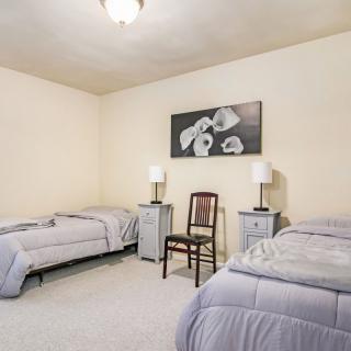 A simple bedroom with two twin beds, nightstands with lamps, and floral artwork on the wall.