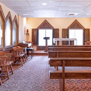 A serene chapel interior with wooden benches and an altar at the front.