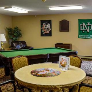 A cozy recreation room featuring a pool table and seating area, adorned with wall decor and a puzzle on the table.