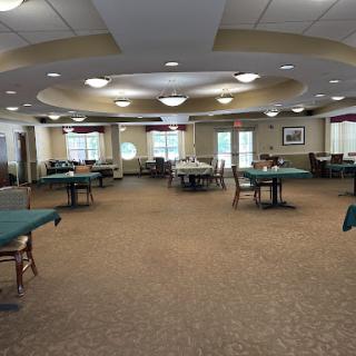 A spacious dining area featuring neatly arranged tables and chairs, illuminated by overhead lights.