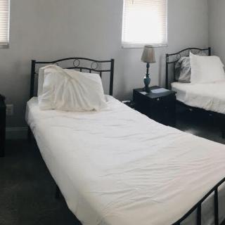 A minimalist bedroom with two twin beds featuring white bedding.