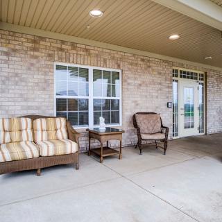A cozy patio with comfortable seating arranged under a covered porch.