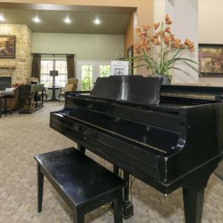 A grand piano in a spacious living room interior, featuring elegant decor and natural lighting.