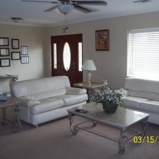 A cozy living room with two white sofas, a coffee table, and a lamp near a window.
