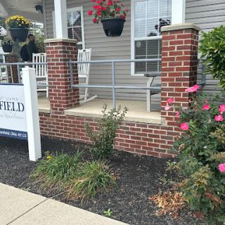 A welcoming porch area with blooming flowers and a sign in front of a residential building.