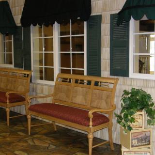 Indoor seating area with benches in front of windows with green shutters.