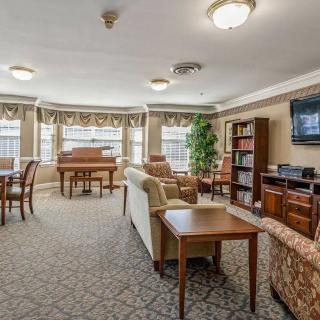 A spacious living room with comfortable seating, a piano, bookshelf, and television.