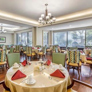 An elegant dining room with neatly arranged tables and chairs, enhanced by large windows and chandeliers.