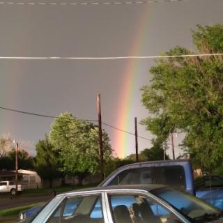 A vibrant rainbow arcs over a stormy sky, creating a striking contrast with the dark clouds.