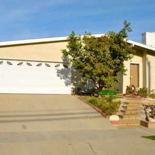 A suburban house with a garage and driveway, surrounded by trees.