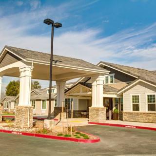A residential building with a covered entrance and a driveway under a blue sky.