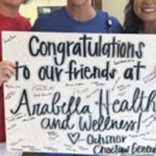 A group holds a congratulatory sign for Arabella Health and Wellness.