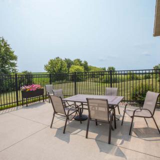 An outdoor patio with a table and chairs overlooking a garden landscape on a sunny day.