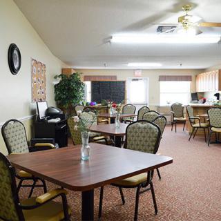 An indoor dining room with multiple tables and chairs, featuring bright lighting and decorative elements.