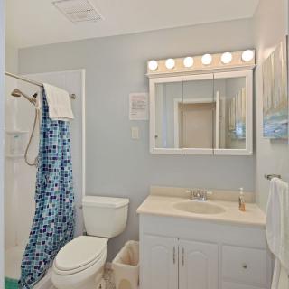 A well-lit bathroom with a vanity, toilet, and shower.