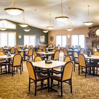 A spacious dining area with neatly arranged tables and chairs, illuminated by elegant chandeliers.
