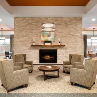 A cozy living room with a modern fireplace, surrounded by four armchairs and a central coffee table.