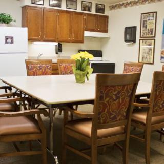 A kitchen and dining area featuring a large table with chairs, wooden cabinets, and kitchen appliances.