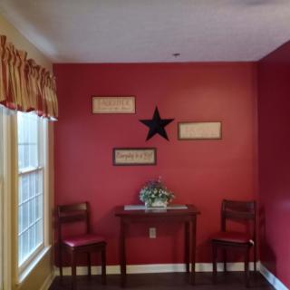 A cozy corner with red walls, featuring two chairs and a small table adorned with decorative items.