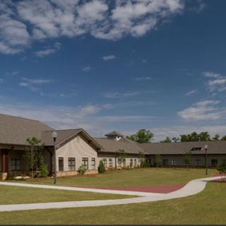 A suburban residential building with a neatly landscaped garden and clear blue sky.