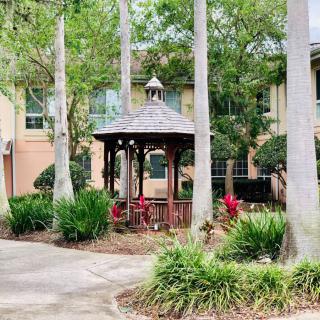 A peaceful garden setting featuring a wooden gazebo surrounded by trees and lush greenery.