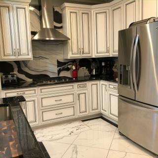 A modern kitchen with stainless steel appliances, elegant cabinetry, and a marble floor.