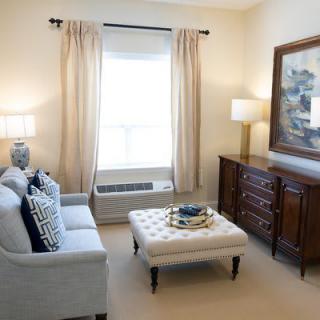 A cozy living room with a sofa and coffee table, decorated with lamps and framed art.