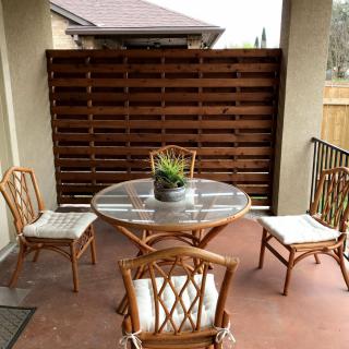 A cozy patio setup with a round table and four cushioned chairs, surrounded by a wooden privacy fence.