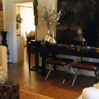 A modern living room area featuring a console table with decorative items, wooden flooring, and stylish furnishings.