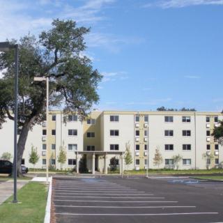 A residential apartment complex with a parking lot in front.