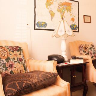 A cozy living room setting with comfortable chairs, a lamp, and a world map on the wall.
