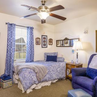 A cozy bedroom with blue-themed decor featuring a single bed and an armchair.