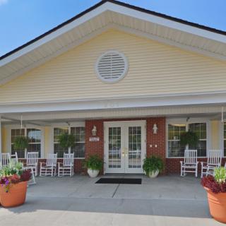 A welcoming building entrance with a porch and potted plants.