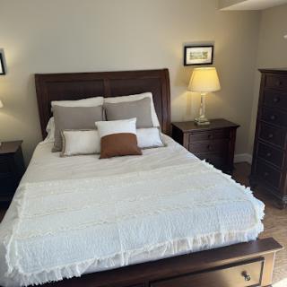 A cozy and inviting bedroom setup featuring a neatly made bed with decorative pillows and warm lighting.