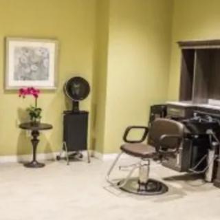 A cozy salon space with a hairstyling chair and hair dryer.