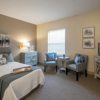 A modern and cozy bedroom with neutral tones, featuring a comfortable bed, chairs, and stylish decor.