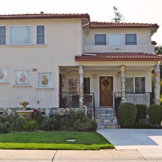 A two-story residential house with a well-maintained lawn and driveway.