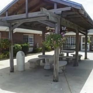 A wooden gazebo with benches and a table, providing a shaded outdoor seating area.
