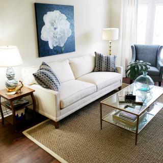 A cozy living room with a white sofa, glass coffee table, and elegant decor.