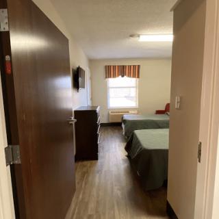 A cozy hotel room with two beds, a television, and a window.