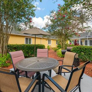 A cozy outdoor patio area with a round table and four chairs surrounded by lush greenery.