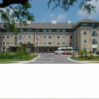 A modern hotel building with a parking area and landscaped surroundings.